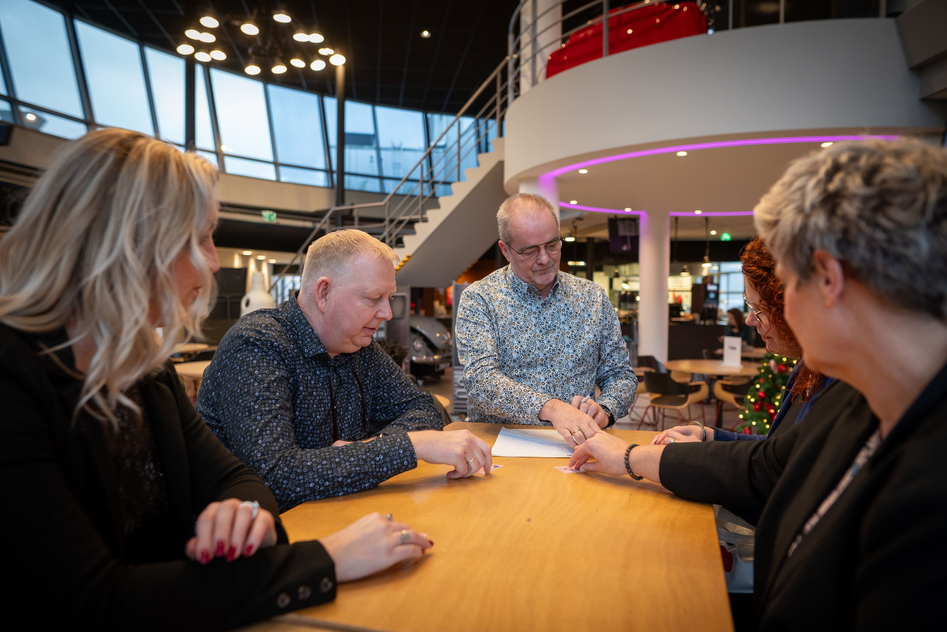 Aan tafel zitten vijf personen. De legitimatiebewijzen worden gecontroleerd.