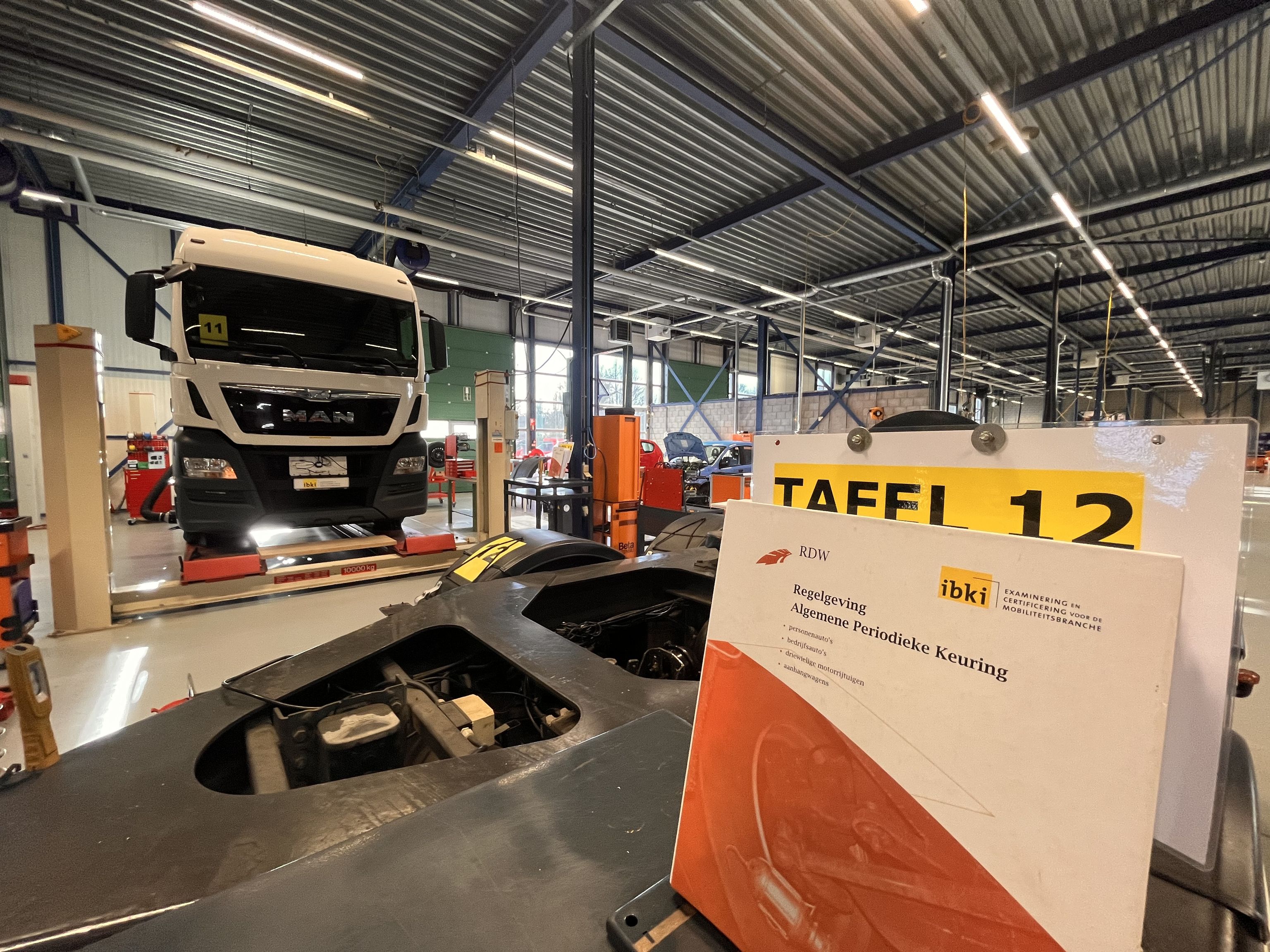 De regelgeving APK bij tafel 12. Op de achtergrond een vrachtauto.
