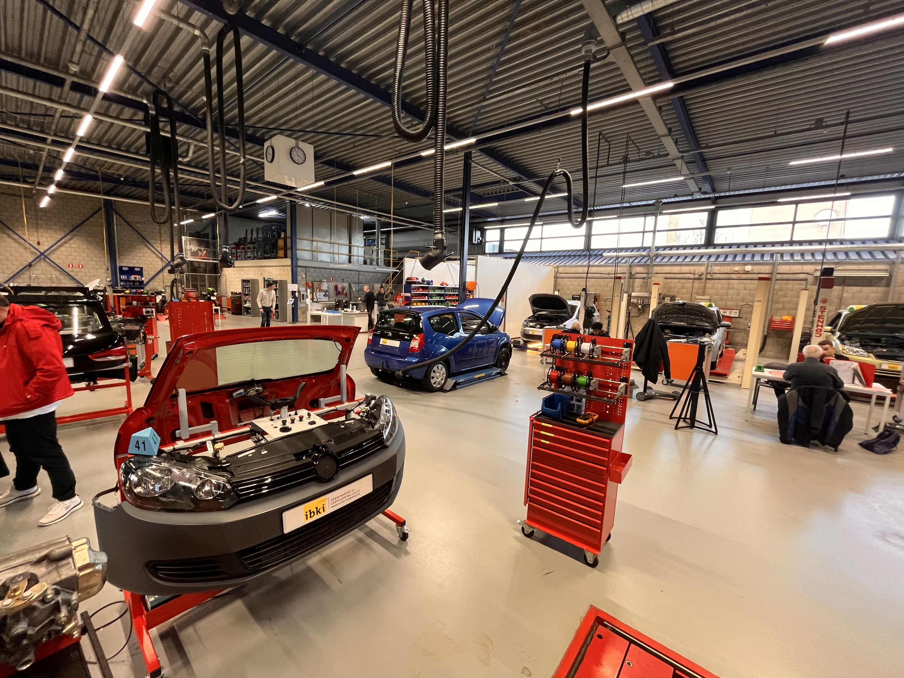 Opstelling van een deel van een auto om aan te sleutelen in de examenhal. Rechts een examengesprek.